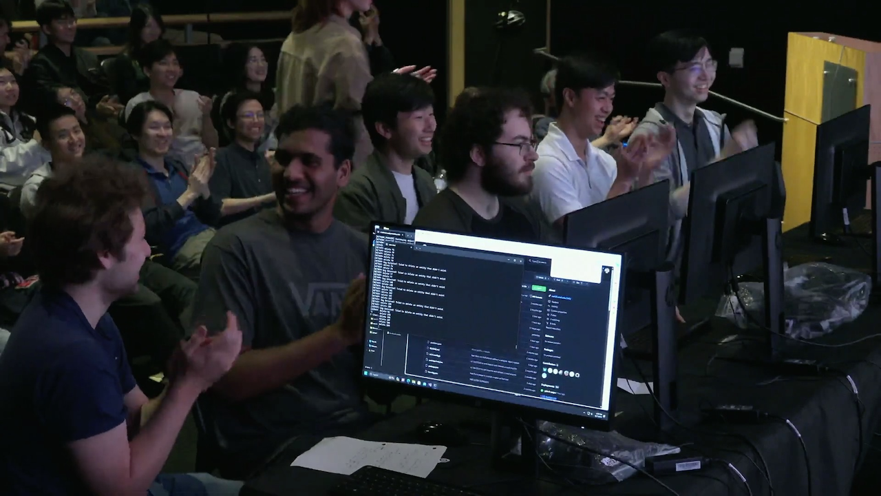 Side angle view of players talking and smiling onstage while the audience claps in the background