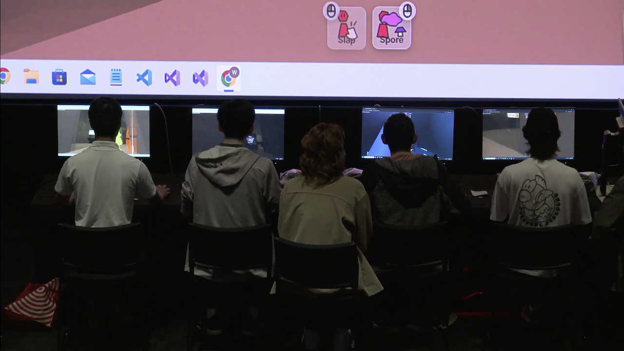 Closeup of players onstage during the demo with their backs to the audience